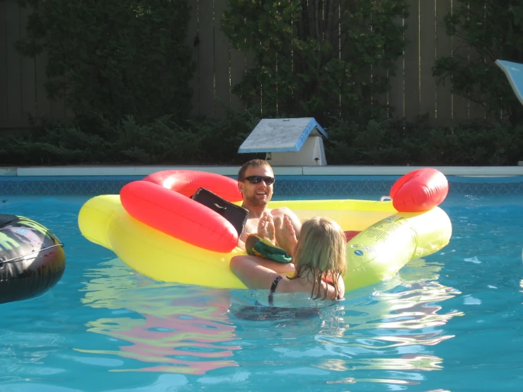 man and little girl in inflatable floating circle in a pool