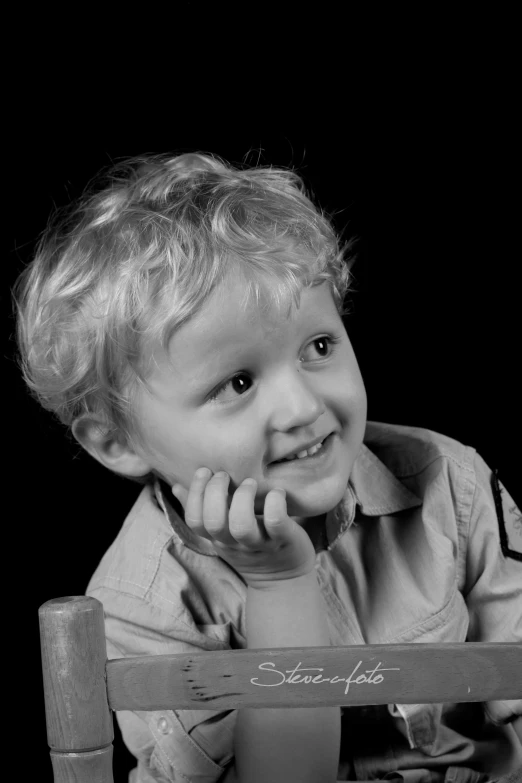 a boy is sitting at the table holding a bottle