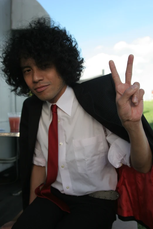 a man in a suit holds up the peace sign