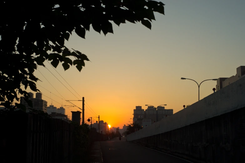 the sun setting in the distance as it sets behind buildings