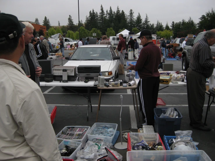 many people are standing near tables with food on it