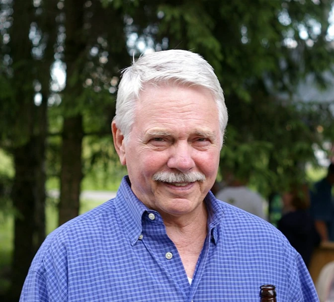 an older man holds up a beer bottle