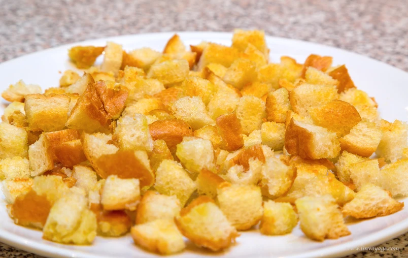 a white plate topped with bread croutons on top of a table