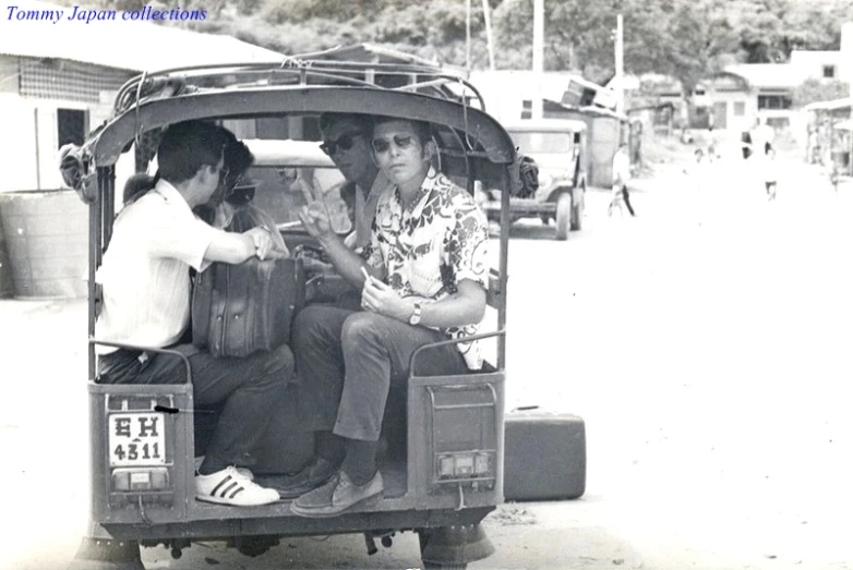 an old black and white po of three people riding on a small cart