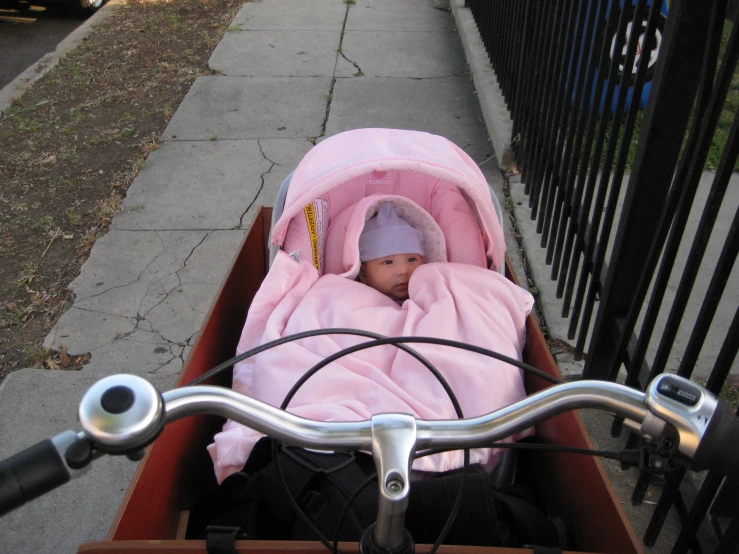 a baby in a pink blanket is wrapped in a stroller