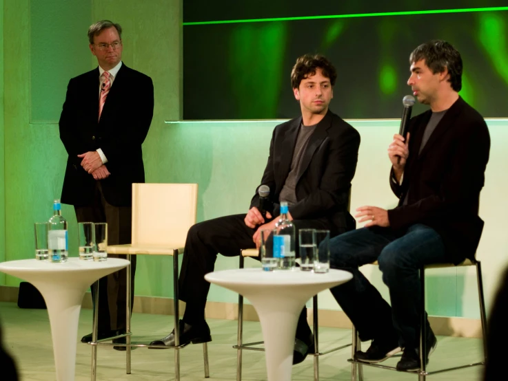 three men speaking into microphones at an event