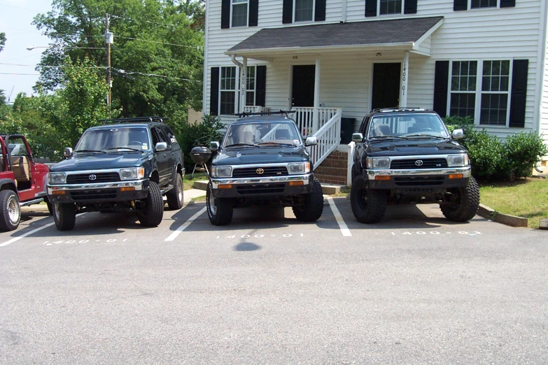 four truck parked in front of a white house