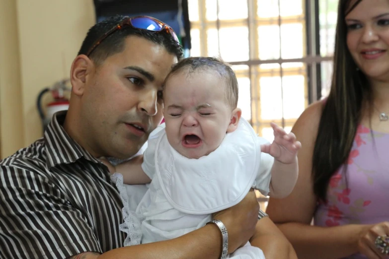 a man holding a baby who is crying