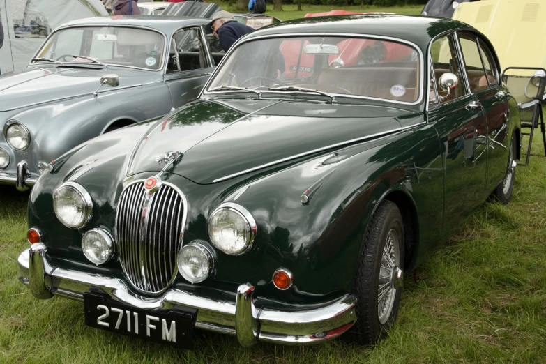 a couple of old fashioned cars sitting on grass