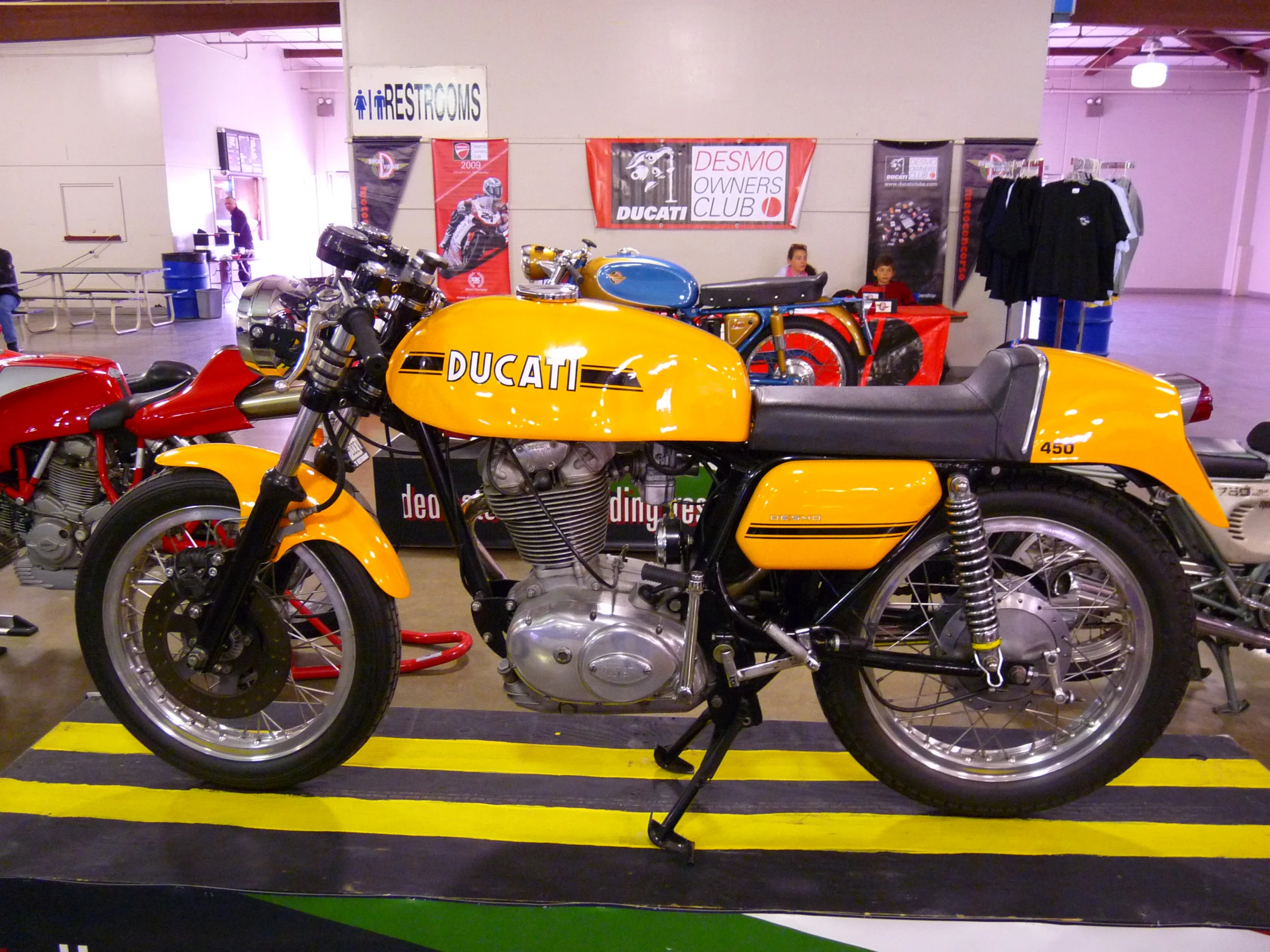 yellow motorcycle parked in an exhibit with other motorcycles