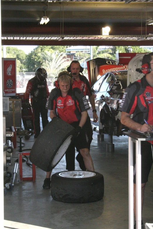 a group of mechanics stand around a black tire