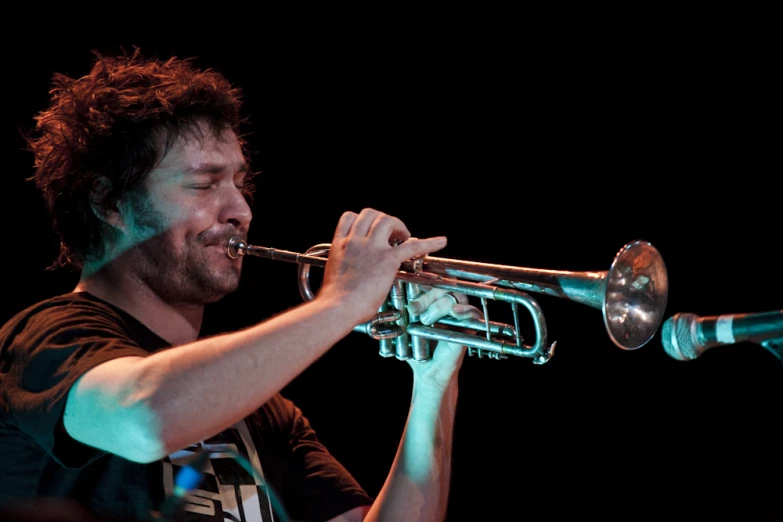 a man is playing a trumpet with his eyes closed