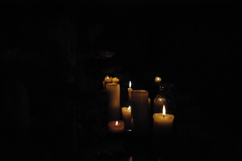 lighted candles sit in a dark room