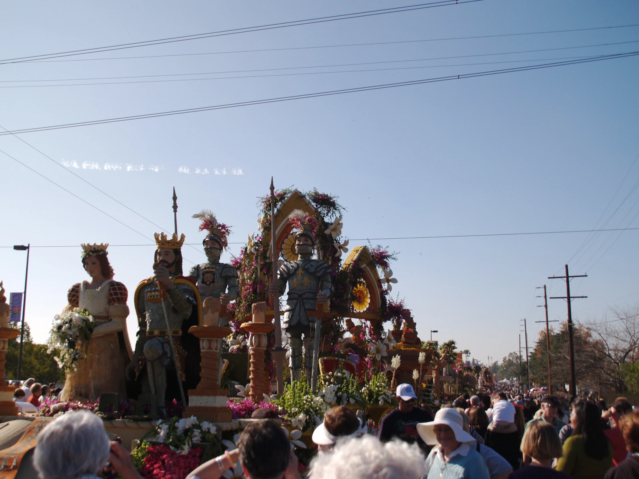 people gathered around and watching two statues being carried on a float