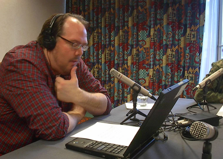 a man sitting in front of a laptop computer wearing headphones