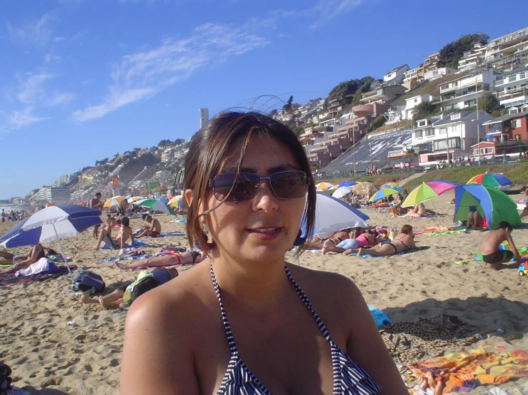 a woman at the beach wearing shades and smiling