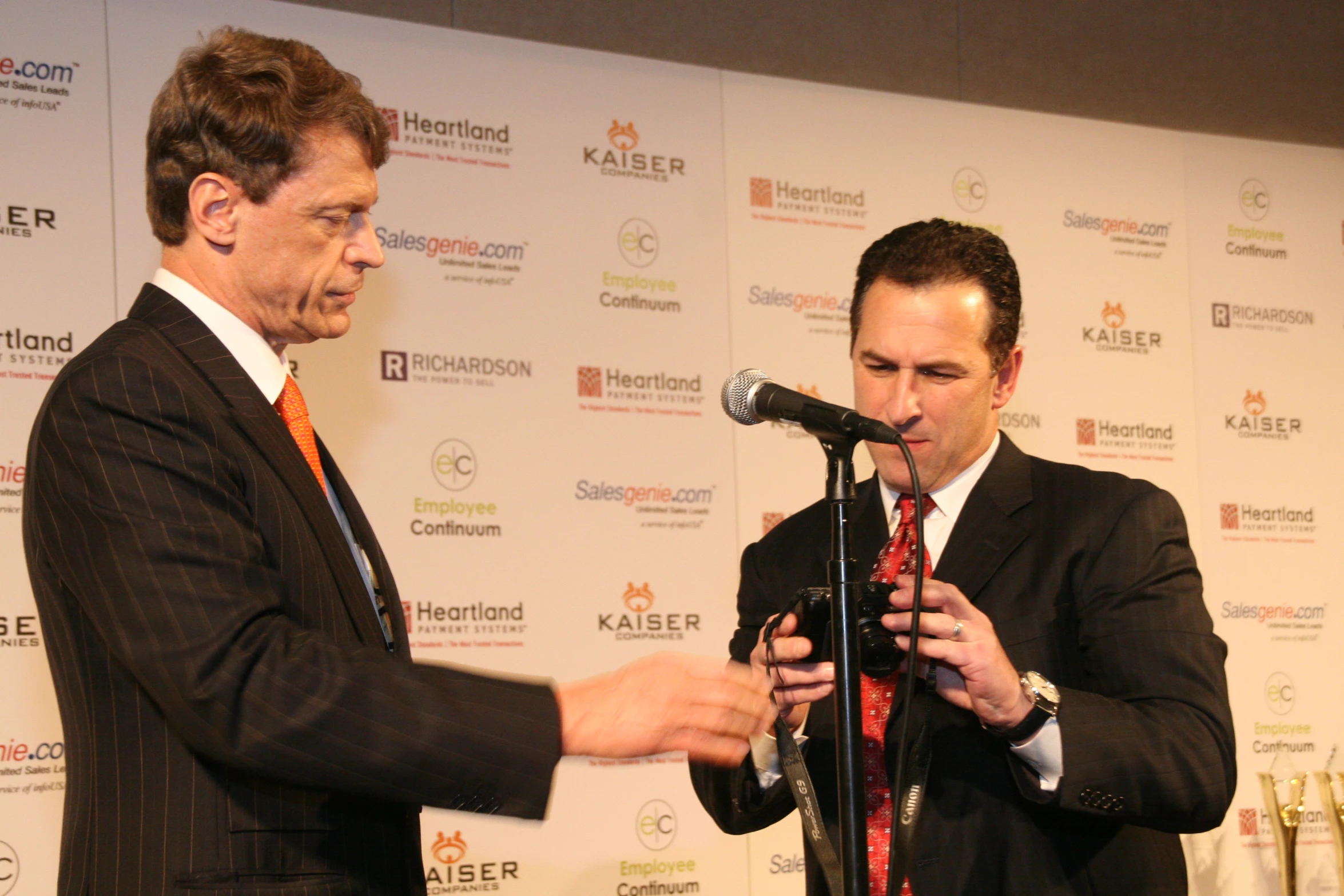 two men are speaking into microphones on a stage