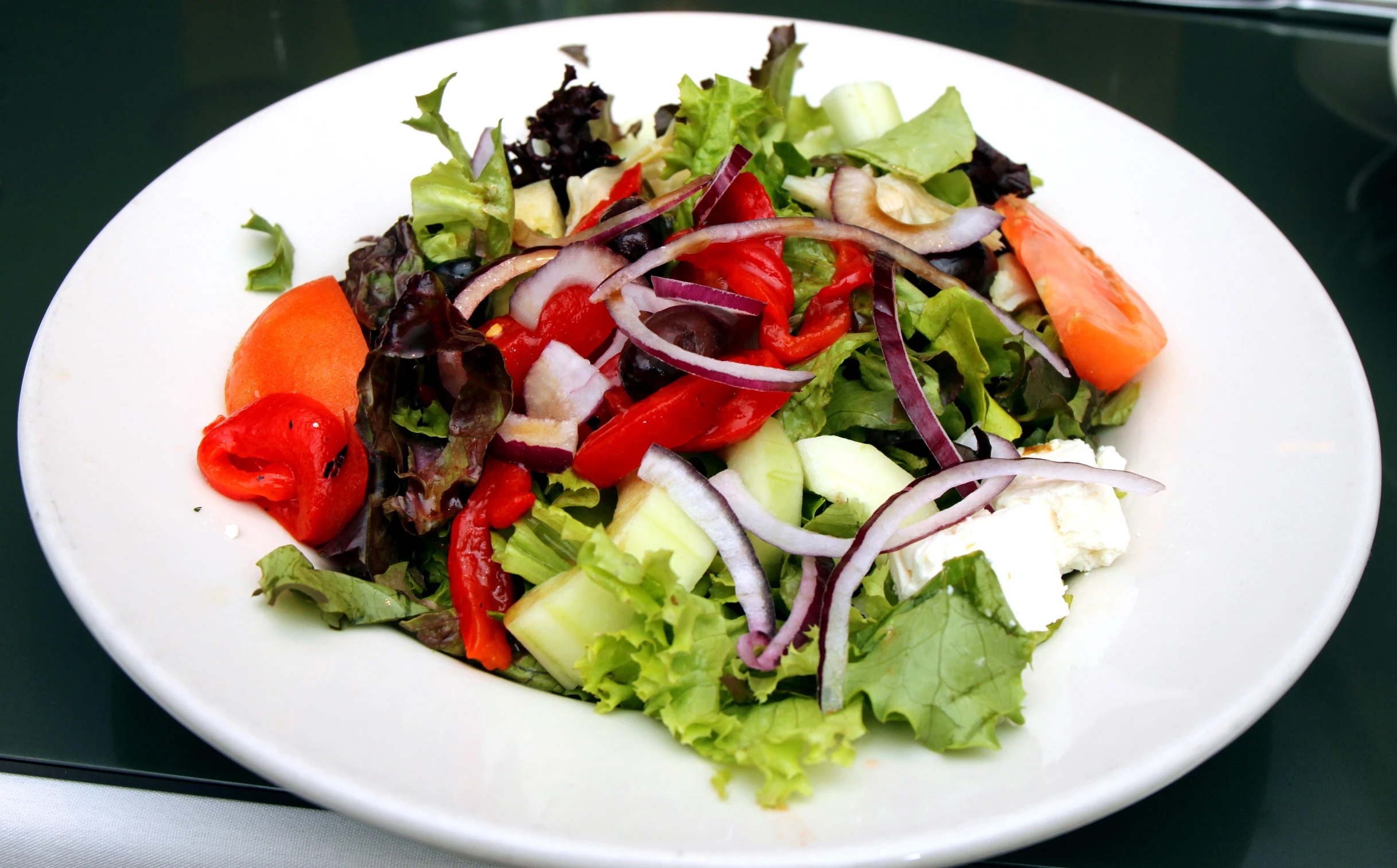 the salad is prepared with onions, tomatoes and peppers