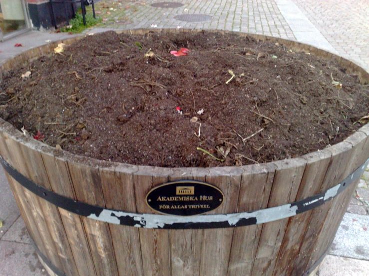 an empty wooden barrel filled with soil outside