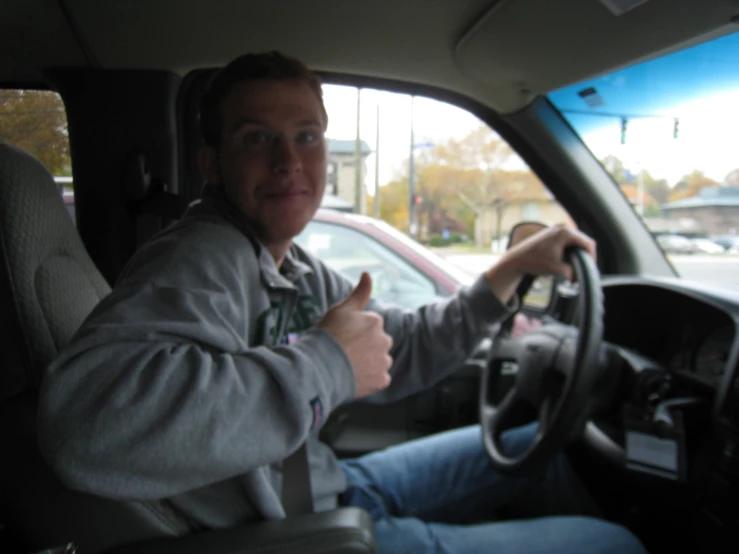 a man driving with headphones on while giving the thumbs up