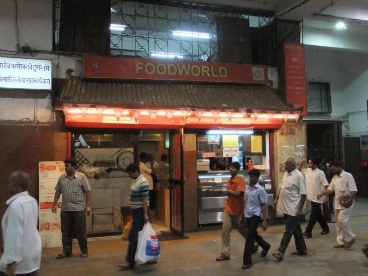 people walk in the street past some food shops