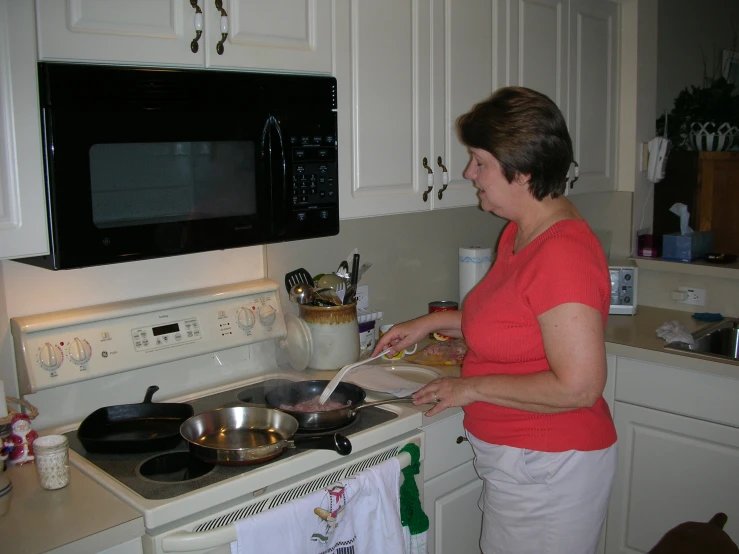 a lady preparing some type of dinner in the kitchen