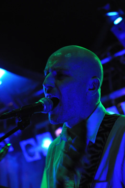 a male singer with a microphone in his hands and lights behind him