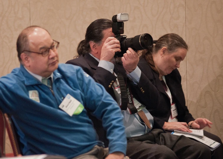 people sitting in chairs, one with a camera