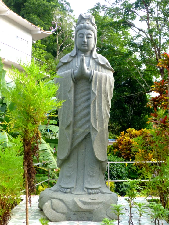 a statue is sitting in front of plants