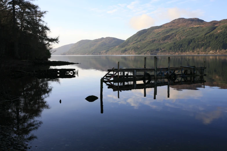 a small dock is on the water near mountains