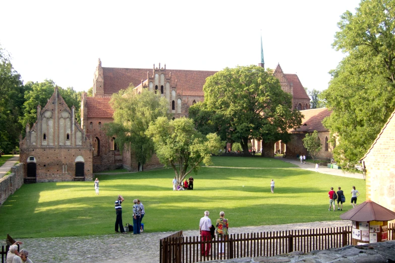 several people are gathered at the park near a castle