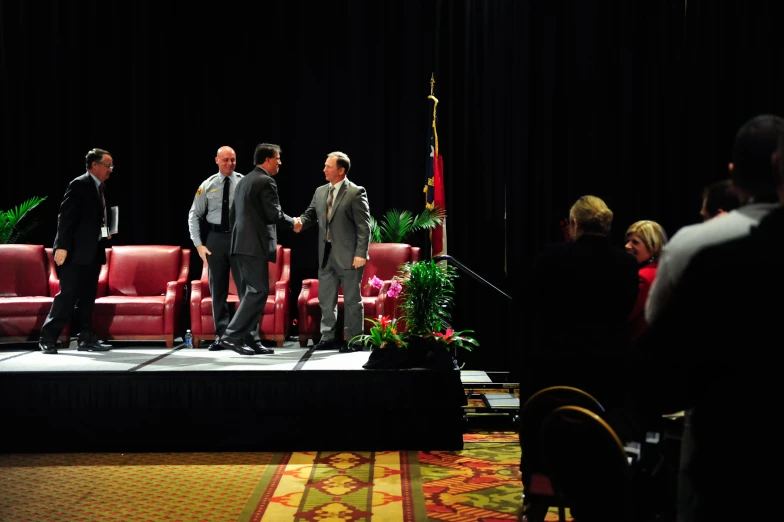 a group of men in suits and tie standing on stage