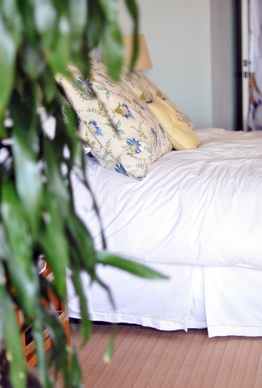 some pillows on top of a bed by some plants