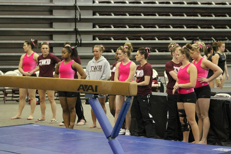 girls in pink and black compete in a gymnastics competition