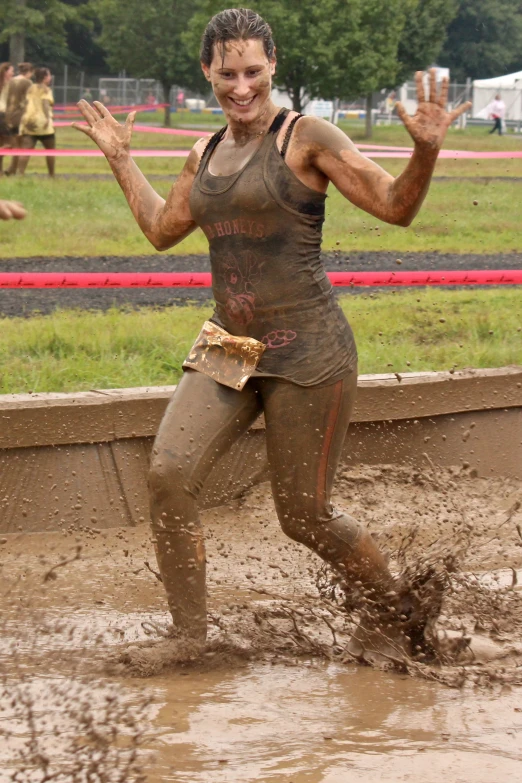 woman in mud suit running through muddy ground