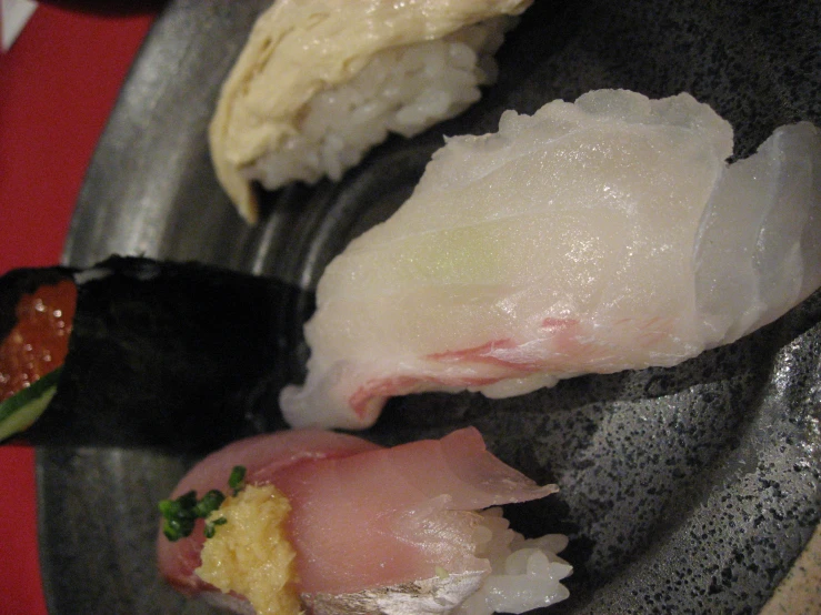 sushi and rolls in a black plate on a red table