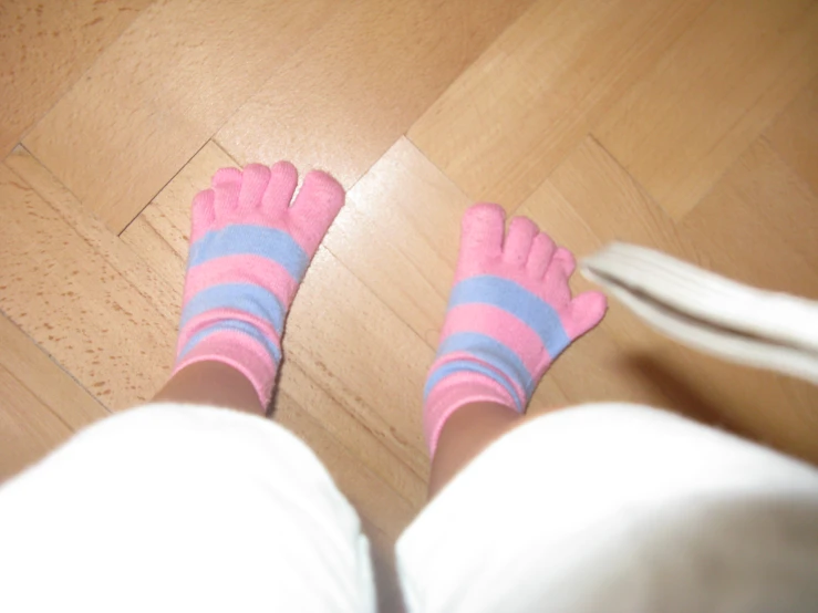 a person with blue socks and pink mitts on their feet