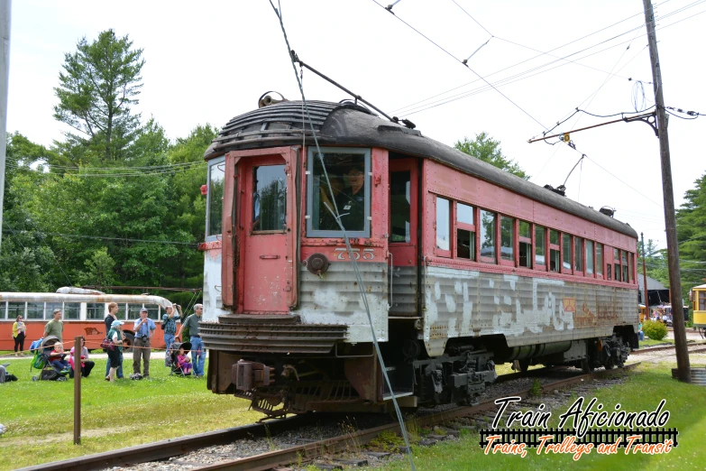 a vintage train on the tracks and several other cars in a field