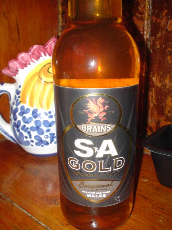 a bottle of sa gold sits on a counter next to a plant pot