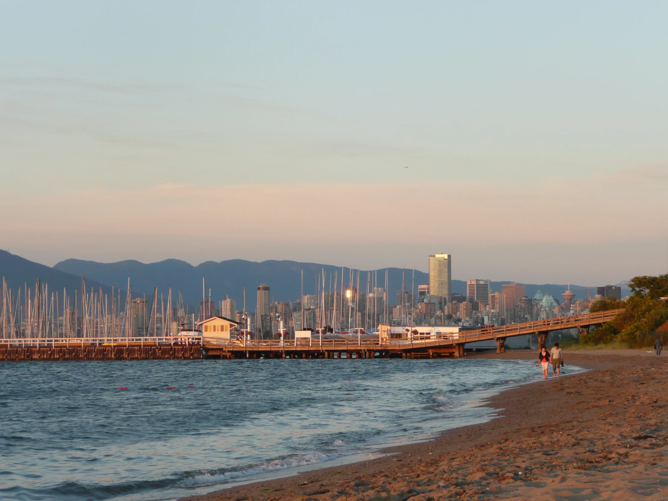 boats in the water near a pier with mountains in the distance