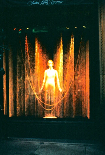 a lighted mannequin is standing in front of curtain