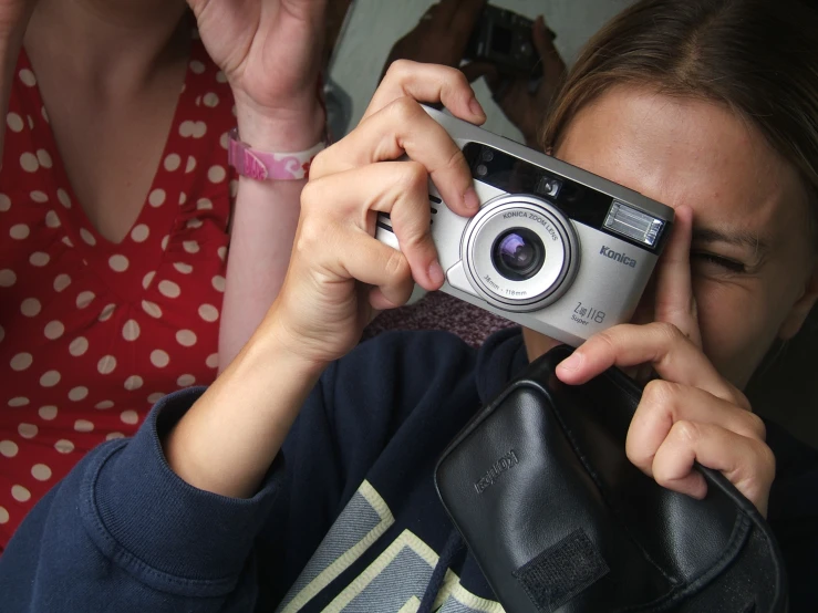 a lady holding a camera while sitting next to a woman