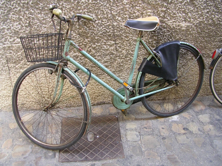 an old, blue bicycle is parked near a wall