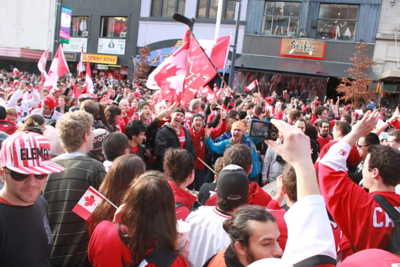 people standing around waving canadian flags and waving