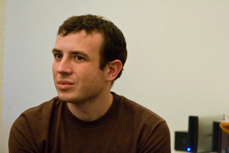 a man wearing a brown t - shirt looks to his left