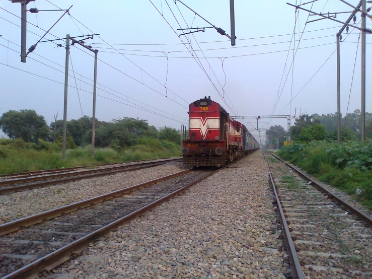 a train on a track going under some power lines