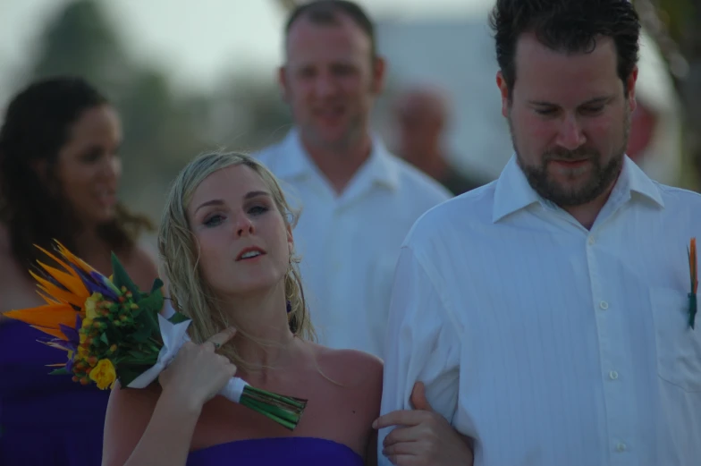 a woman dressed in purple and blue holding a bouquet