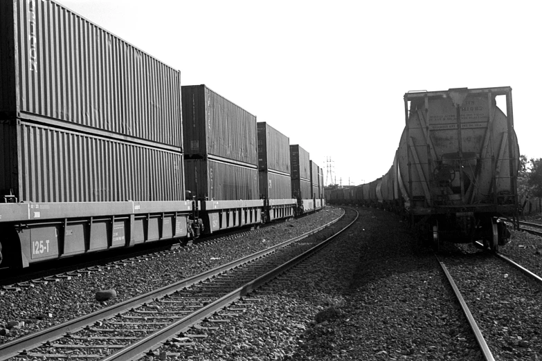 the black and white po shows a cargo train on tracks with other trains
