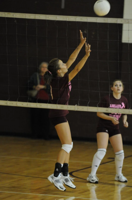 two girls are playing volleyball in a gymnasium