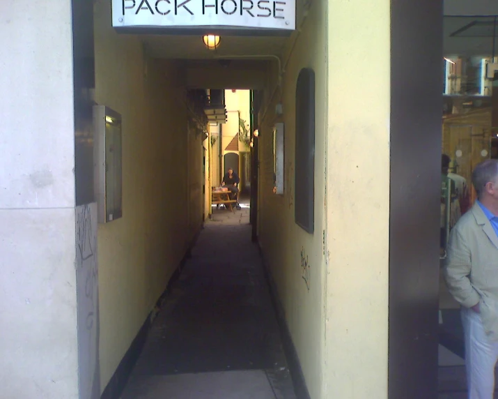 man walking down yellow corridor with pack horse on it